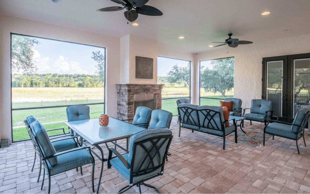 Covered patio with outdoor seating and fireplace in a custom-built home in Clermont, FL by Bridgethorn Construction.