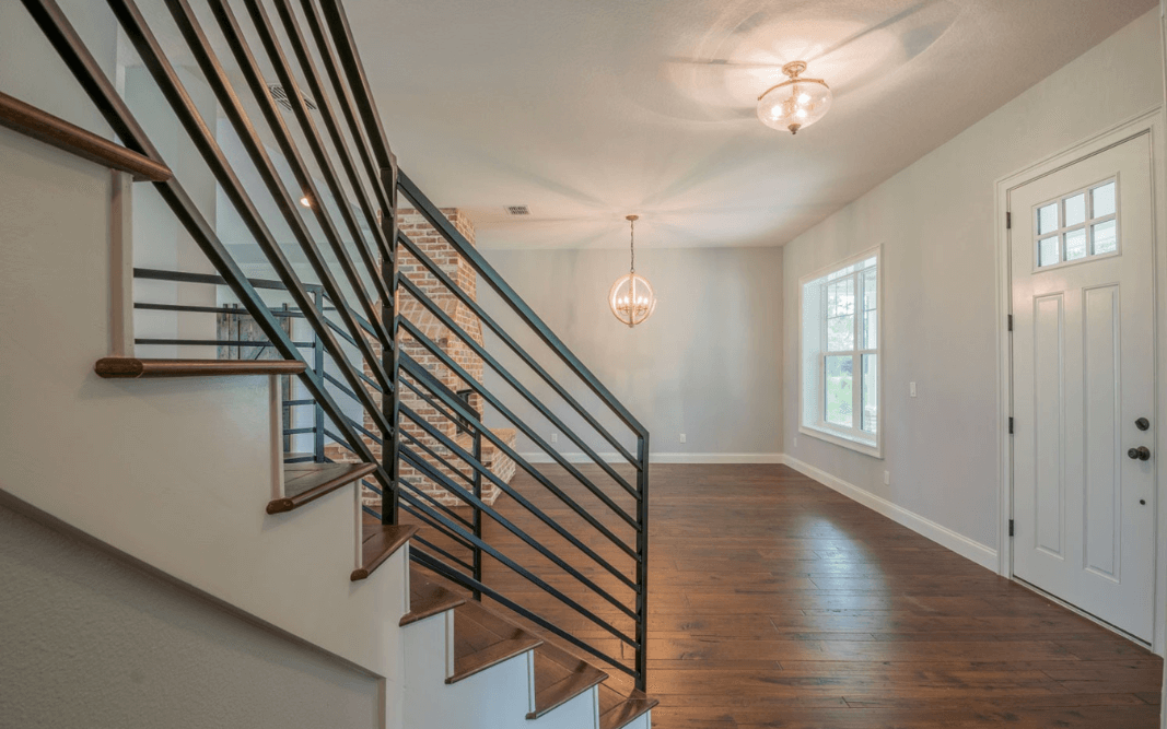 Contemporary metal staircase with wooden steps leading to the second floor, blending rustic and modern styles in a custom home.