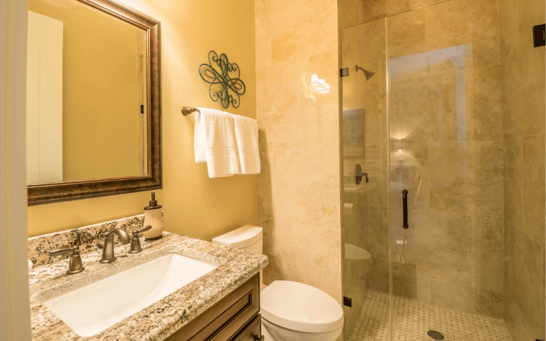 Elegant bathroom with granite countertop, glass shower, and custom fixtures in a custom home in Clermont, FL.