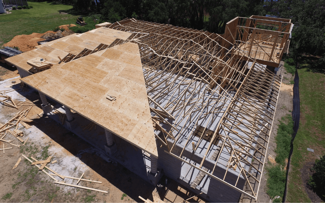 Aerial view of roof framework for a custom home under construction in Clermont, FL, by Bridgethorn Construction, showcasing the building process.