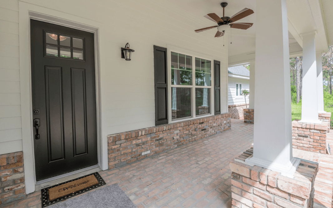 Inviting farmhouse-style entryway with columns and a dark front door, adding character to this custom home in Clermont.