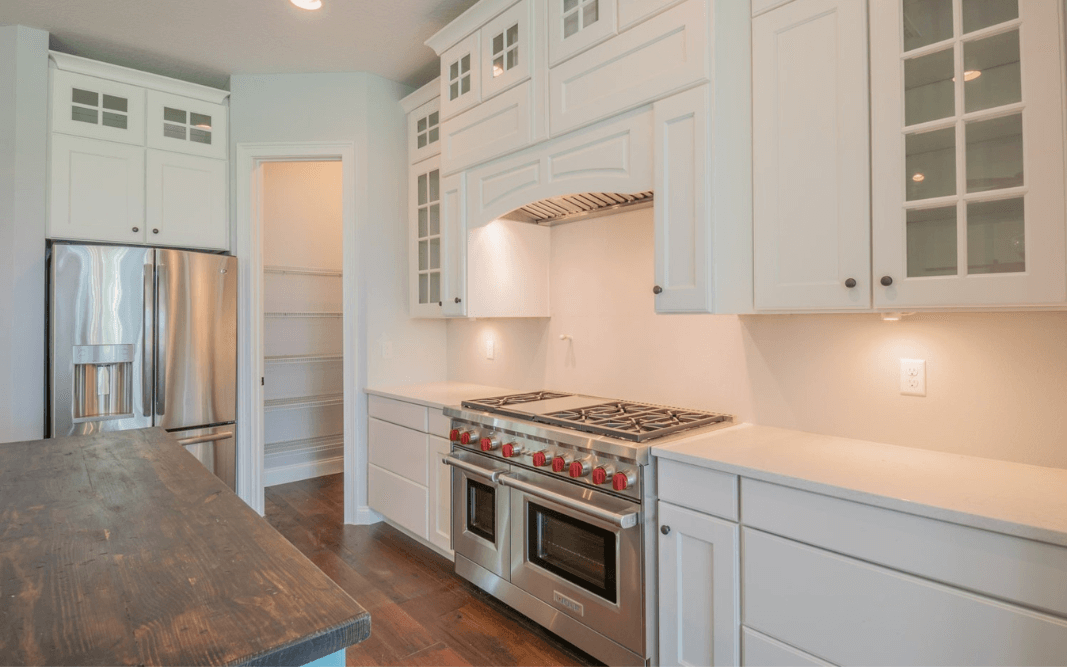 Farmhouse kitchen featuring stainless steel double ovens, custom cabinetry, and open shelving, built by Bridgethorn Construction.