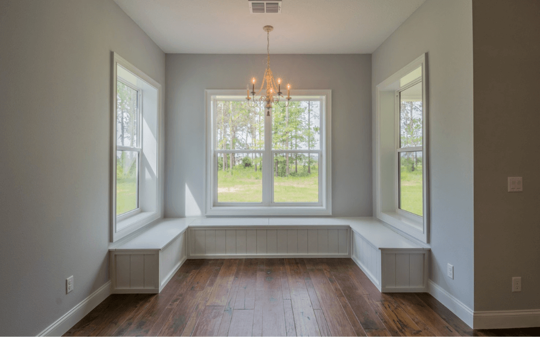 Bright and cozy window nook with built-in seating, perfect for relaxing, part of a custom farmhouse home in Clermont.