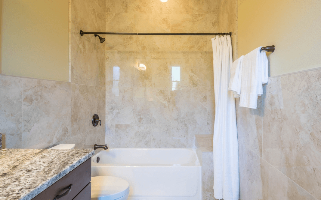 Elegant bathroom with marble tile and a granite countertop in a custom-built home in Clermont, FL, designed by Bridgethorn Construction.