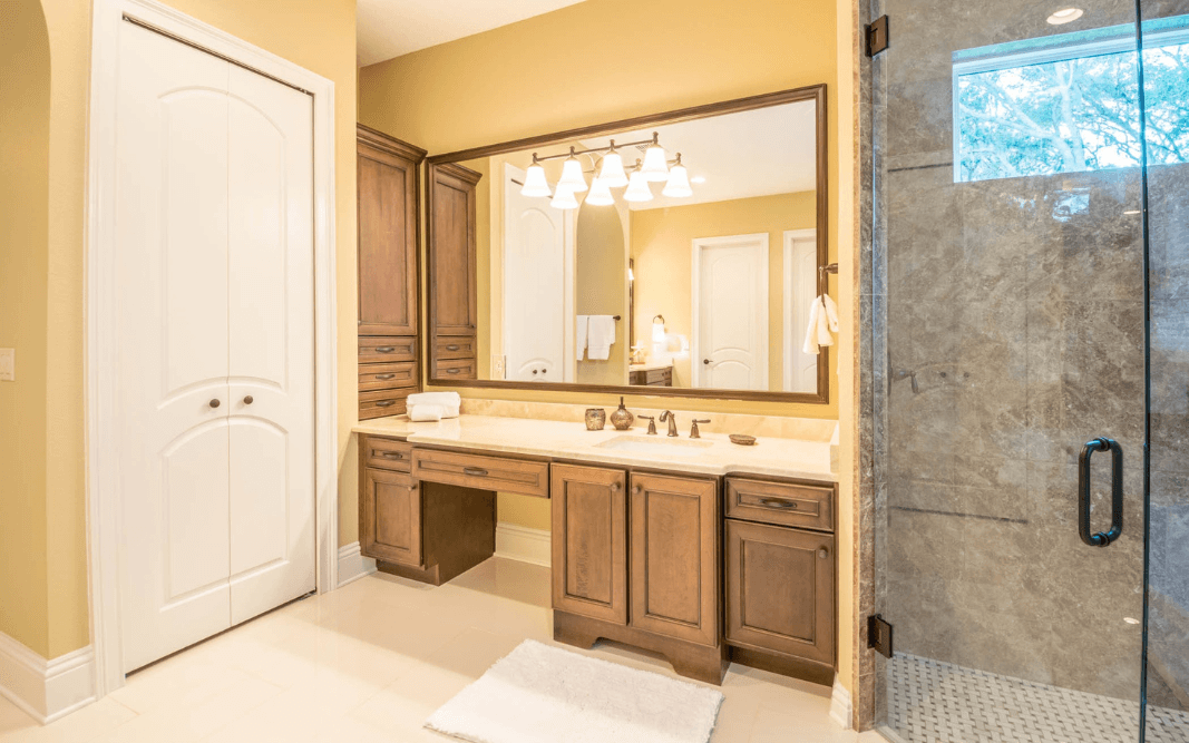 Elegant bathroom vanity with wood cabinetry and a large mirror in a custom-built home in Clermont, FL, designed by Bridgethorn Construction.