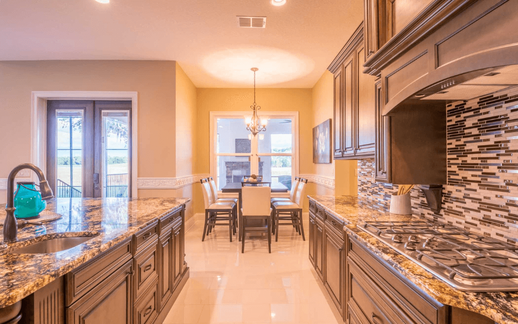 Luxury kitchen with granite countertops, wood cabinetry, and open dining area in a custom Clermont, FL home.